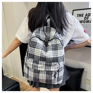 Detail showing the black and white grid texture and sturdy dual zippers of the backpack