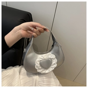 Borsa hobo argento con cuore in pizzo tenuta in mano per mostrare le dimensioni