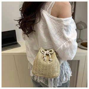Stroh-Eimertasche mit Kordelzug von Model getragen für einen lässigen Strandurlaub-Stil
