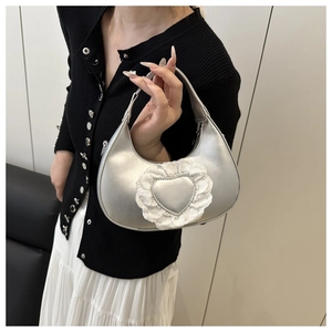 Dettaglio della borsa a mezzaluna argento con finiture in pizzo bianco e cuori