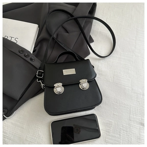 Detail view of small black PU leather crossbody bag with smartphone for size comparison