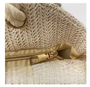 Detail of smooth gold zipper and beige lining on woven straw shoulder bag