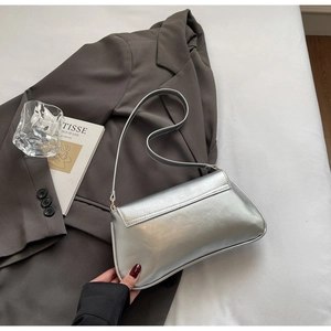 Détail du sac baguette argenté métallisé sur tissu avec une esthétique minimaliste