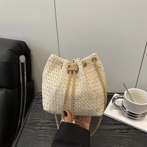 Chic woven bucket bag in cream white with a gold chain strap and drawstring closure