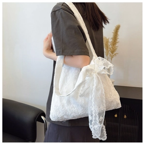 Detailed embroidery and large lace bow accent on a white canvas tote bag for women