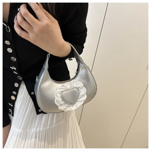 Dettaglio della borsa hobo argento con patch a cuore in pizzo e finitura metallica