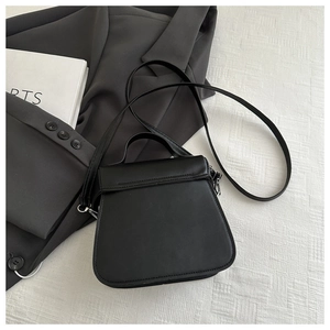 Rear view of a black structured bucket bag showing premium stitching and leather handle