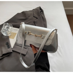 Gros plan du sac à bandoulière argenté texturé avec boucle mors dorée et fini métallique