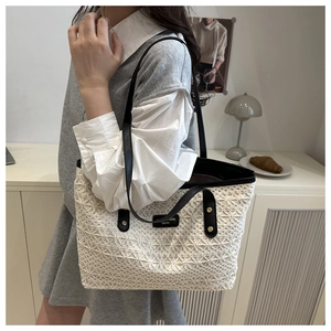 Close-up of hollow straw tote bag with black leather handles shown in a lifestyle setting