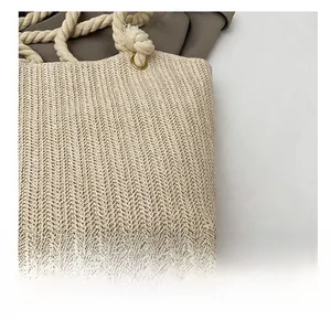 Close-up of woven herringbone texture and rope handle detail on beige tote bag