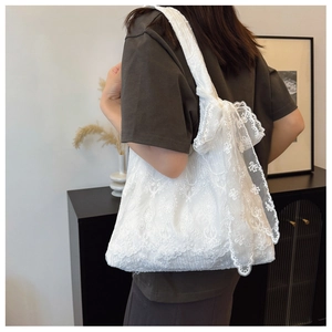 Close-up of white floral lace embroidery and large ribbon bow on shoulder tote bag