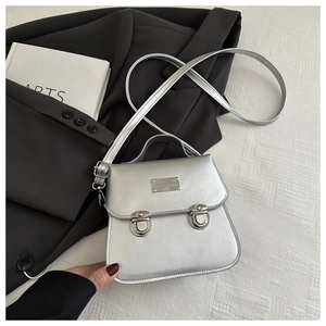 Detail of silver metallic mini bag with dual round push-lock buckles and top handle