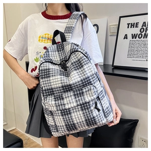 Close-up of black and white checkered canvas backpack featuring a front zipper pocket