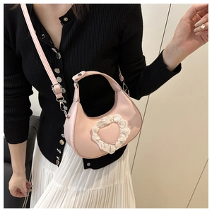 Pink heart-shaped hobo bag featuring lace trim details and adjustable crossbody strap