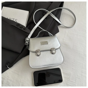 Silver mini square bag shown next to a smartphone to demonstrate the product scale