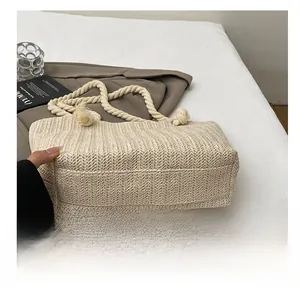 Detail of reinforced woven bottom on beige straw tote bag with cotton rope handles