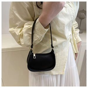 Detail of black pebbled leather texture on a chic half-moon handbag with gold zipper