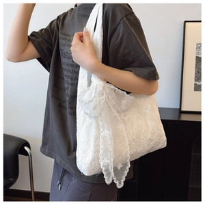 Detailed shot of white floral lace tote bag featuring a large decorative bow on the side