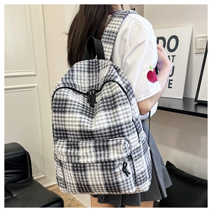 Detail of checkered backpack featuring large capacity main pocket and black knot zipper pull