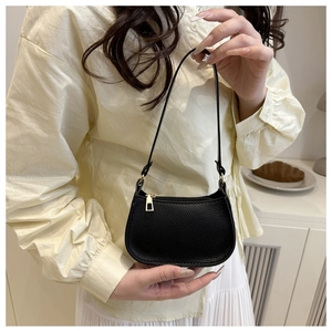 Detail of minimalist black pebbled leather texture on half-moon bag with gold zipper