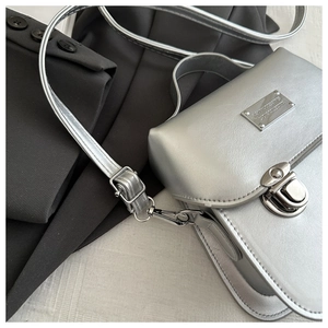 Close-up of silver square bag with metallic coating and rectangular metal buckle