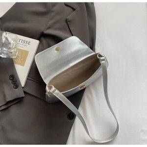 Détail du sac argenté métallisé avec fermoir magnétique doré et doublure intérieure beige