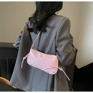Rosafarbene Halbmond-Tasche mit Schleifen-Detail auf einer grauen Anzugsjacke präsentiert