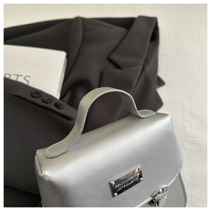 Close-up of metallic silver square handbag with high-shine finish and metal buckle