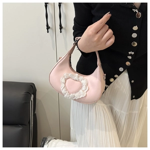 Dettaglio della borsa a mezzaluna rosa con cuore in pizzo bianco e finitura in pelle liscia