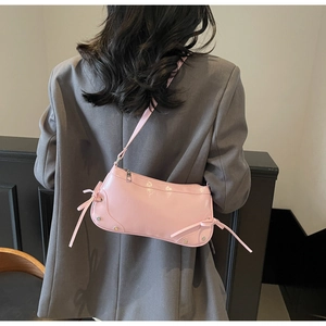 Detailansicht einer rosa Lackleder-Halbmondtasche mit Zierschleife und Metallnieten