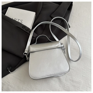 Detail of silver metallic handbag with flap closure and adjustable shoulder strap