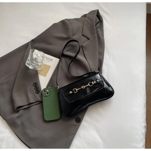 Détail du sac vintage en cuir verni noir avec boucle mors dorée et design chic élégant