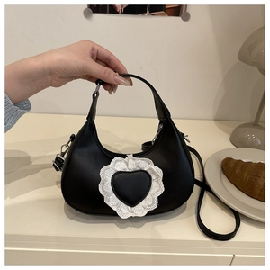 Dettaglio borsa a mezzaluna nera con inserto a cuore in pizzo e finiture argentate