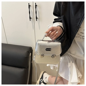 Detail of silver metallic bucket bag with dual buckle closure and top handle