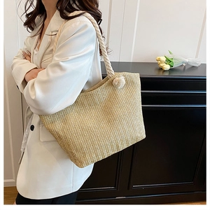 Detail of straw woven tote bag featuring white rope handle and textured chevron pattern