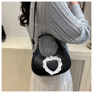 Dettaglio della borsa nera a cuore con bordo in pizzo bianco indossata da una modella