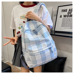 Detail of a blue and white gingham backpack featuring a front pocket and braided zipper pulls