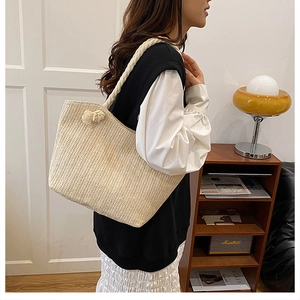 Detail shot of cream woven straw tote bag featuring thick rope shoulder straps and knot detail