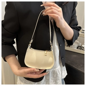 Detail of off-white lychee grain leather texture and gold zipper on a modern hobo bag