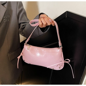 Detailaufnahme der rosa glänzenden Handtasche aus Kunstleder mit Nieten und Schleifen