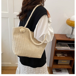 Detail view of woven straw tote bag featuring thick white cotton rope shoulder straps