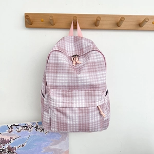 Detailed view of a pink plaid canvas backpack with front zipper pocket and side pockets
