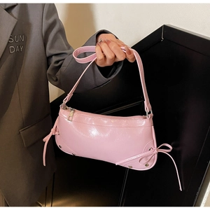 Detailaufnahme der rosa Lackleder-Baguette-Tasche mit seitlicher Schleife und Schultergurt