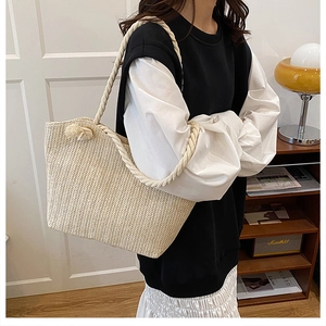 Model showing a large cream woven straw tote bag with thick rope shoulder straps
