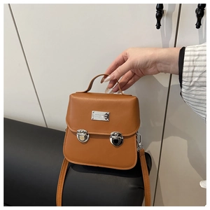 Detail view of brown leather bucket bag with silver metal nameplate and double push locks
