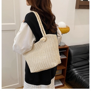 Detail of beige straw bag showing dense V-shape weave texture and knot cotton rope handle
