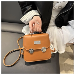 Close-up of caramel brown vintage satchel bag with silver dual buckles and metal tag