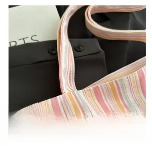 Detail of neat stitching on multi-color striped canvas tote bag with pink and orange patterns