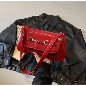 Gros plan sur le sac sous l'aisselle en cuir verni rouge avec boucle mors argentée