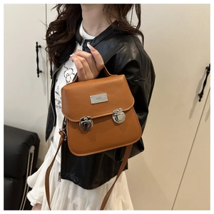 Detail of a brown leather bucket bag showing silver buckles and top handle on a model